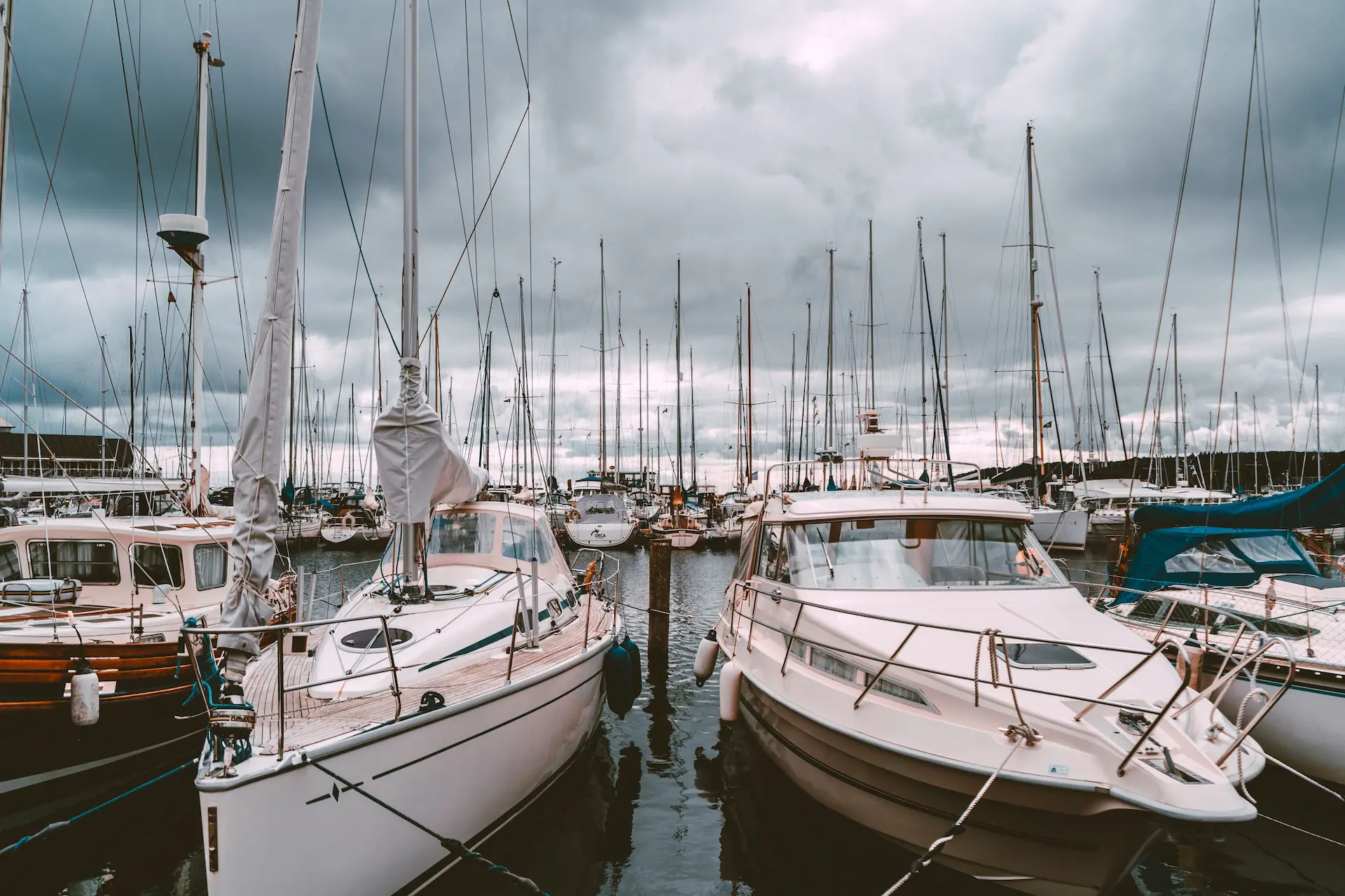 Yachts and motor cruisers lying in their berths at a marina under a grey sky